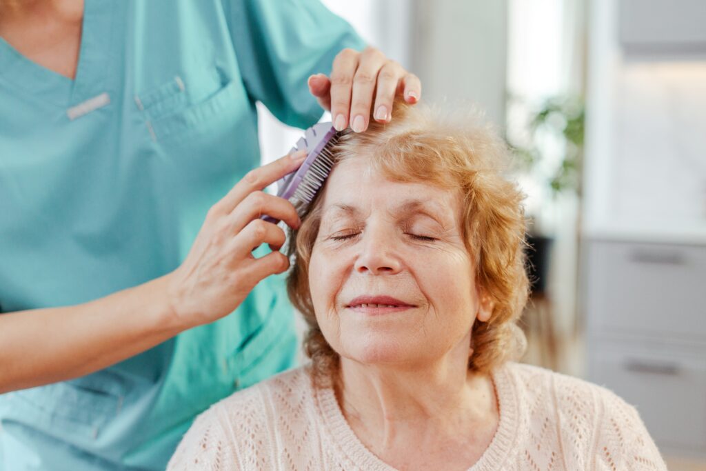 Smiling,Nurse,Brushes,A,Senior,Woman's,Hair,,Showing,Care,And